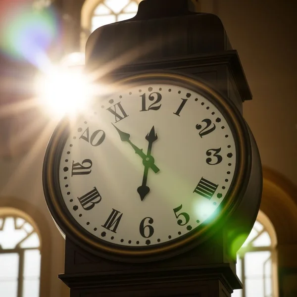 Eine Uhr, die 12:00 Uhr anzeigt, um die Bedeutung von at noon zu veranschaulichen
