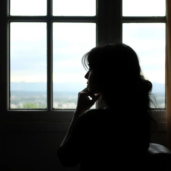 Image showing a person thoughtfully looking out a window, illustrating the concept of Come To Terms With